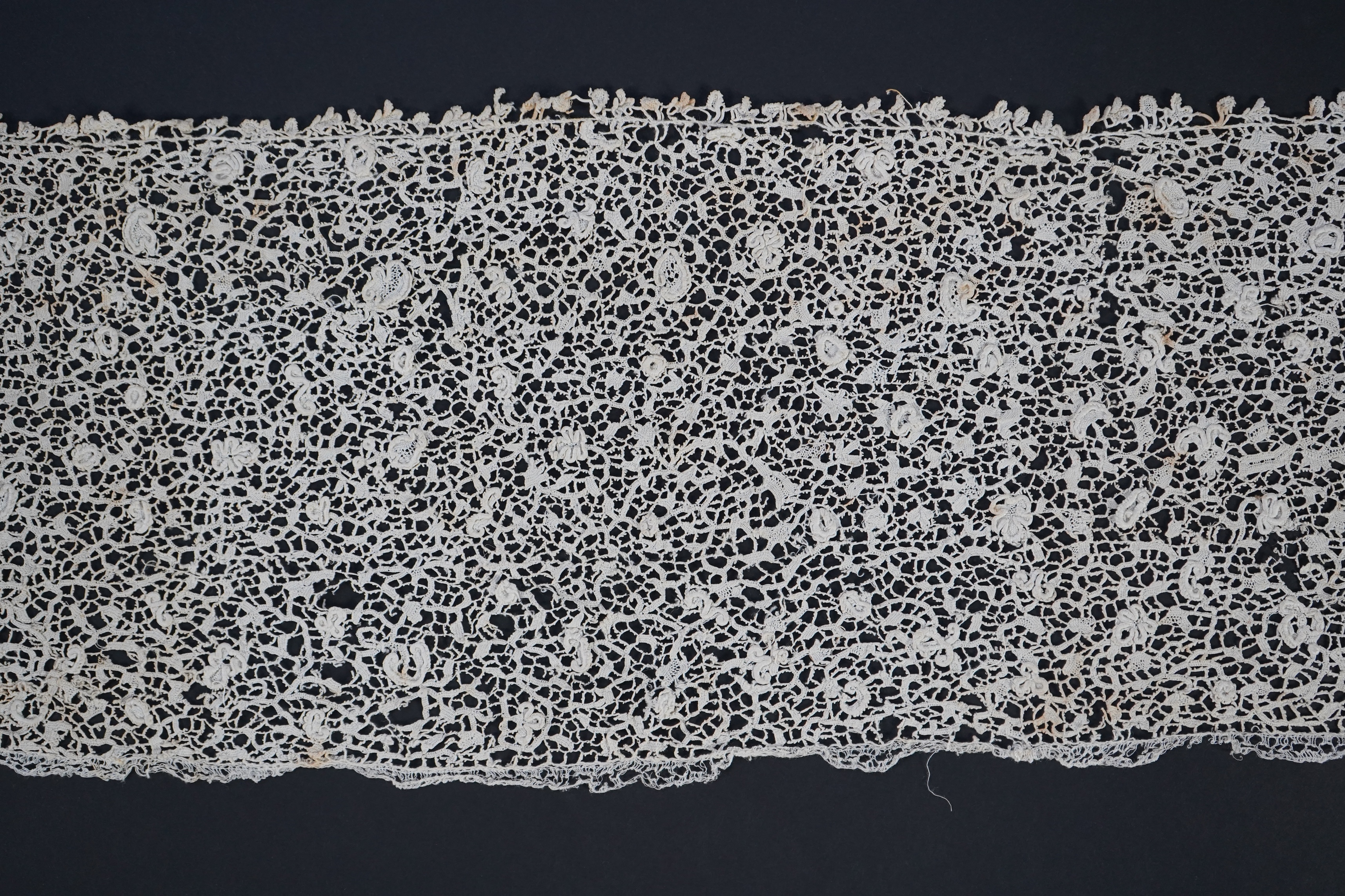 A late 17th century wide flounce of Point de France needle lace, together with a narrower flounce, both with raised elements of the design in the style of Point de Rose, but less so. This lace was very popular with the F